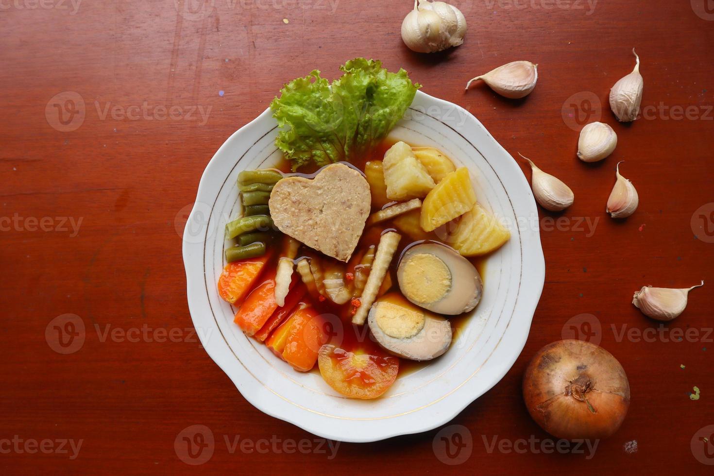 selat solo es una ensalada tradicional de indonesia. hecho de huevos duros, garbanzos hervidos, zanahorias hervidas, croquetas de patata y lechuga, bistec o bistik. servido en mesa de madera foto