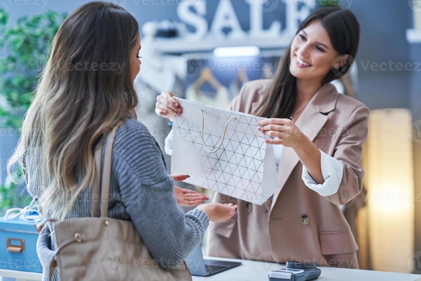 Woman seller and buyer in clothes store photo