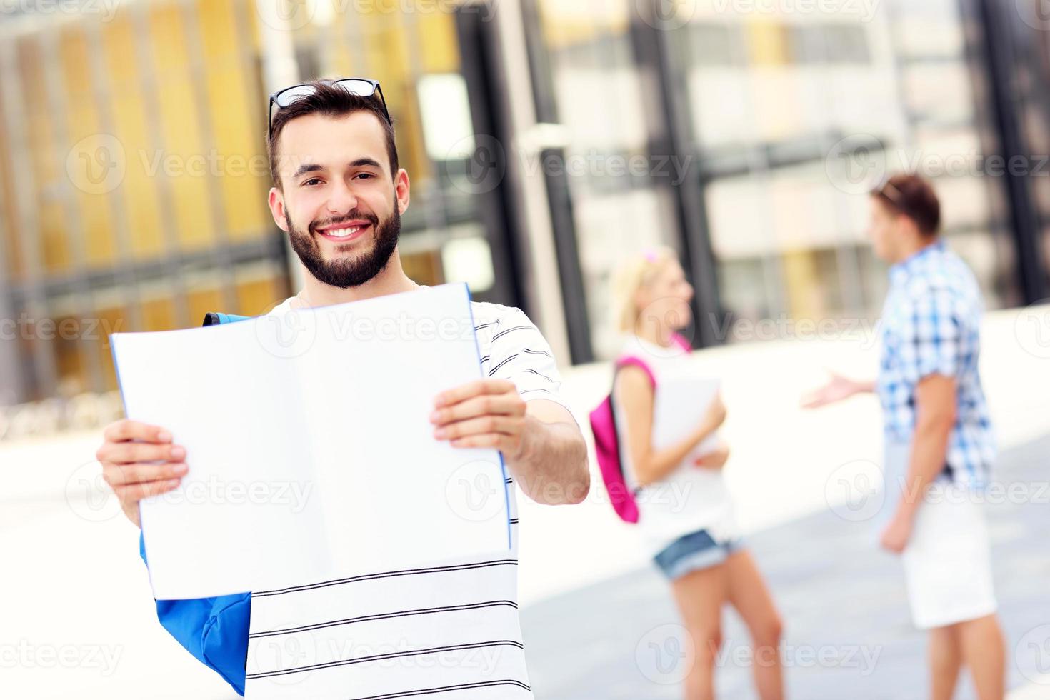 Young student standing in the campus with an open notebook photo