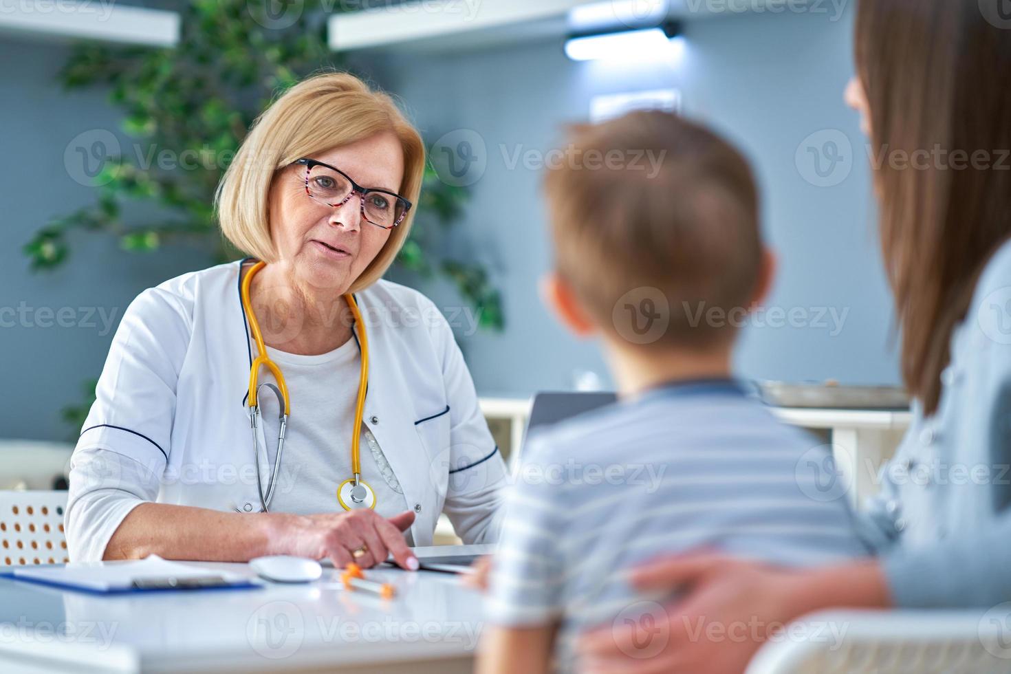 Pediatrician doctor examining little kids in clinic photo