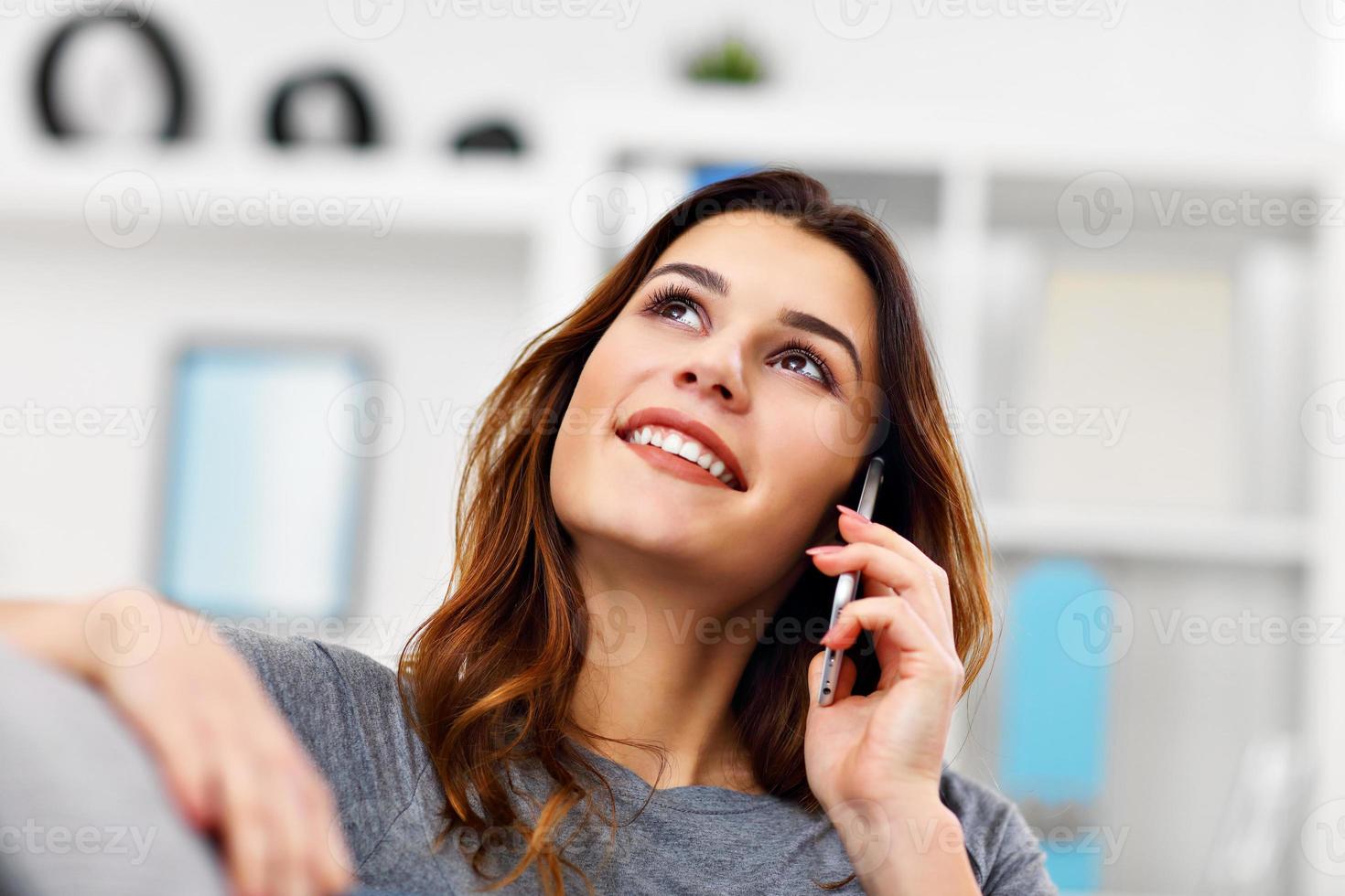 Happy adult woman using phone at home in the living room photo