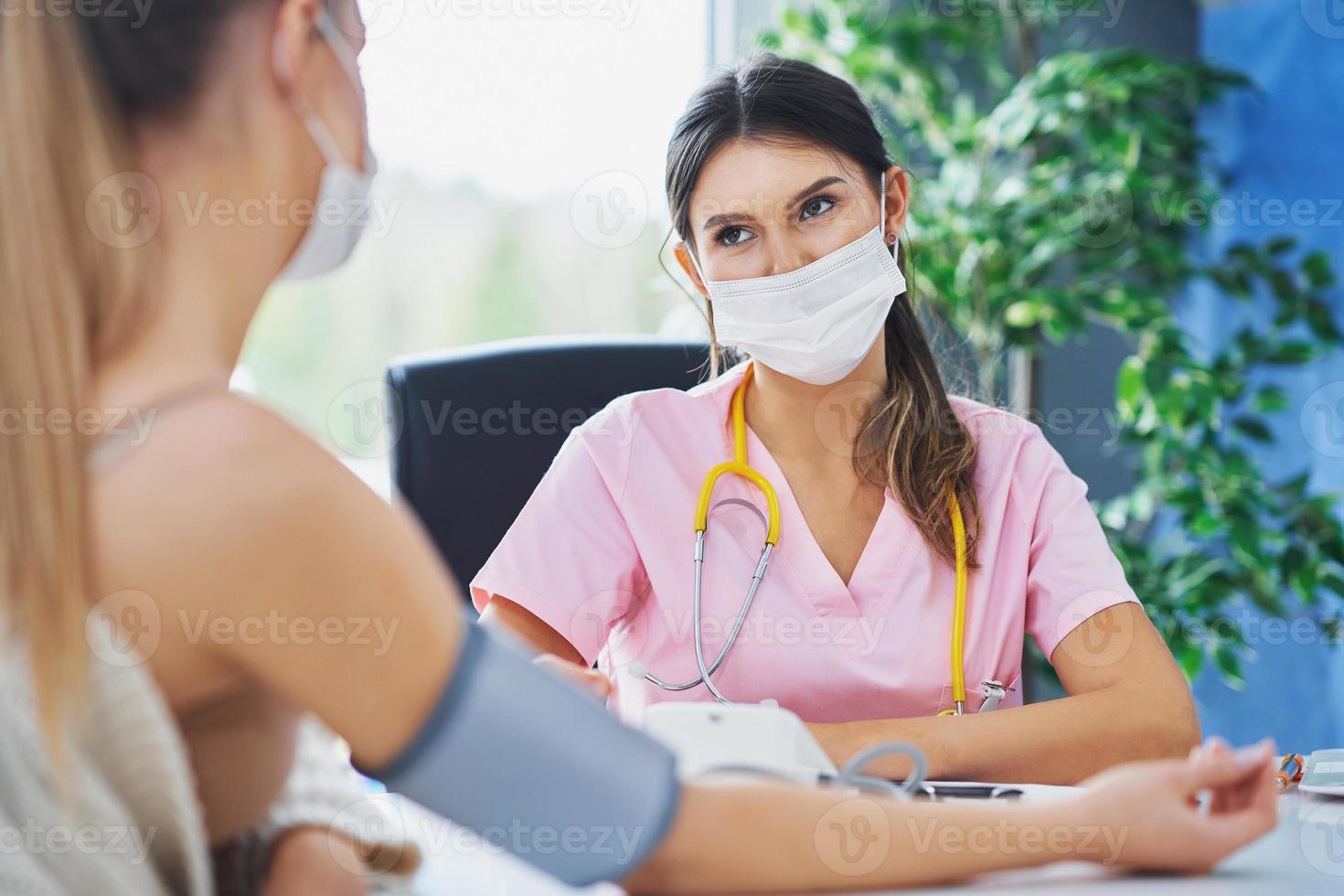 Doctor in mask explaining diagnosis to her female patient photo