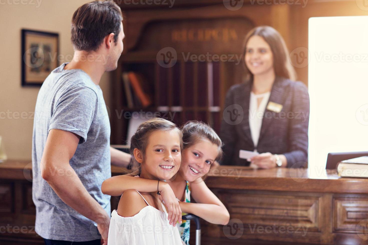 Happy family checking in hotel at reception desk photo