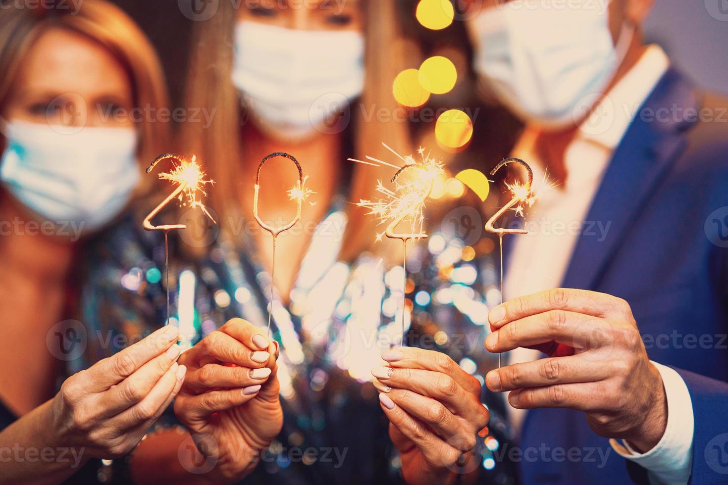 Beautiful young friends in masks having fun at New Year's Eve Party 2022 photo
