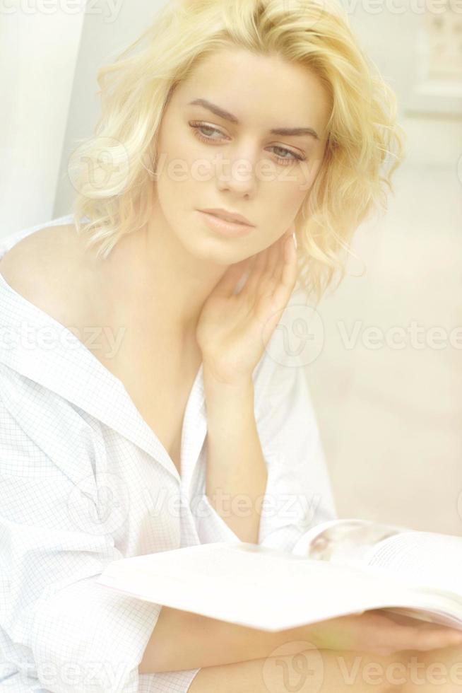 mujer bonita joven leyendo un libro en la ventana foto