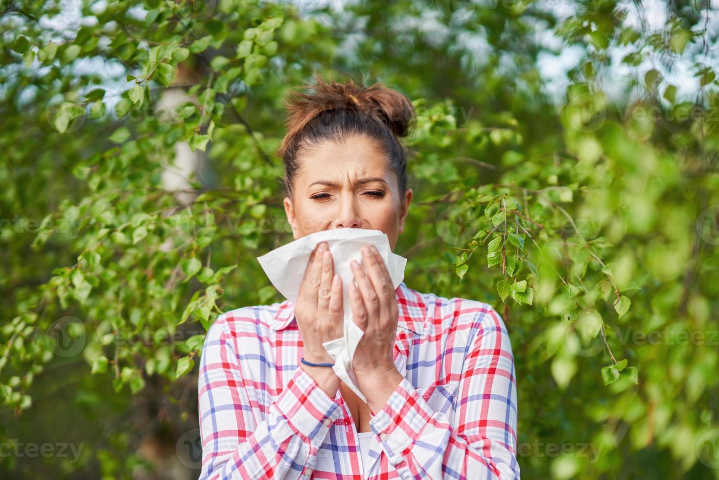 Young woman having allergic symptoms with tissue photo