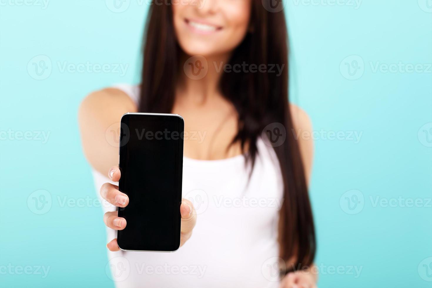 Woman using smartphone against blue wall background photo