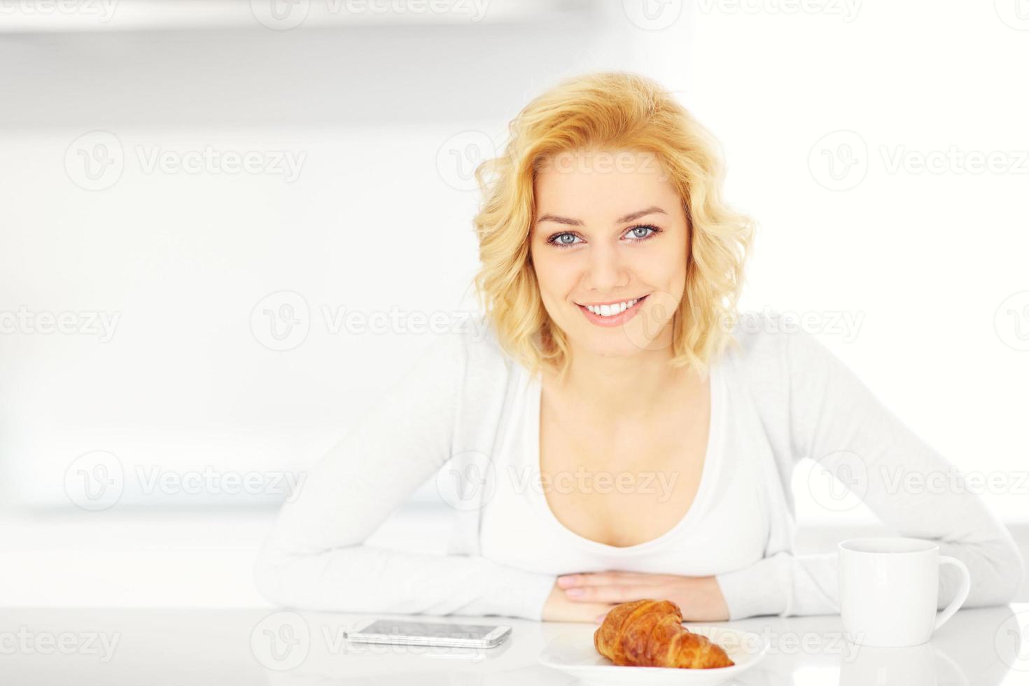 Young woman with smartphone in the kitchen photo
