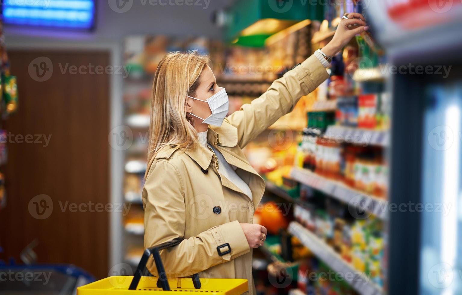 Adult woman in medical mask shopping for groceries photo