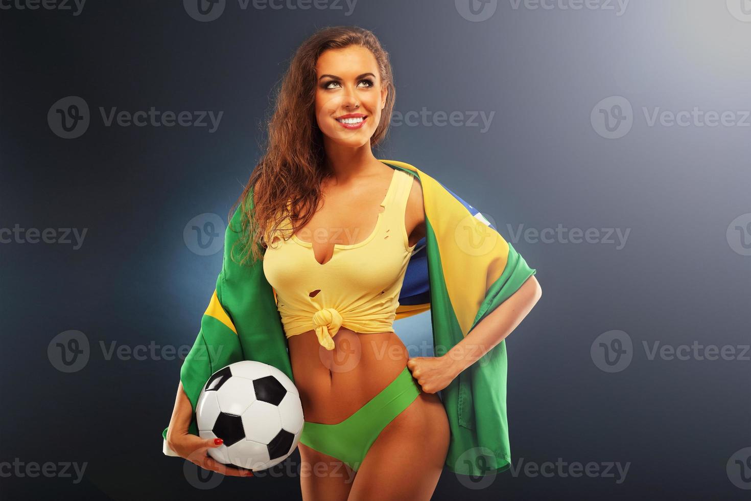 Happy Brazilian fan cheering with flag and football photo