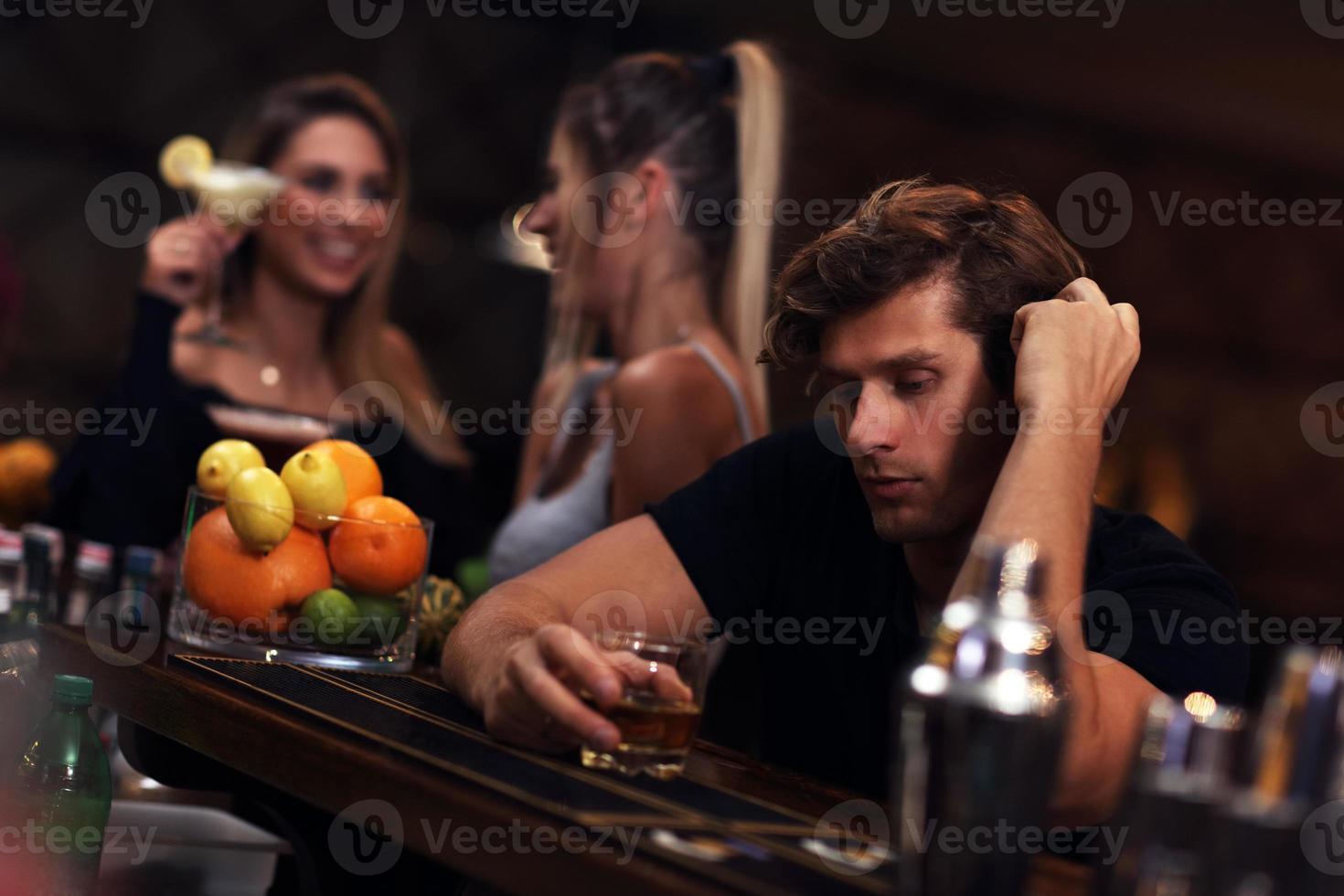 Young man sitting alone in bar with a glass of whisky photo
