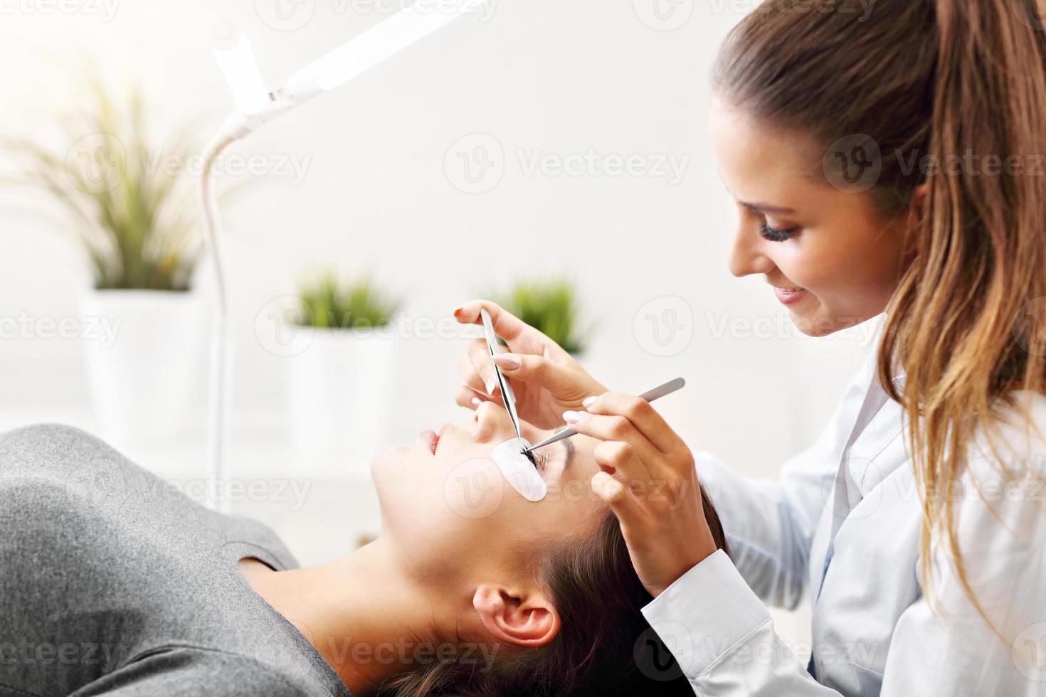 Adult woman having eyelash extension in professional beauty salon photo