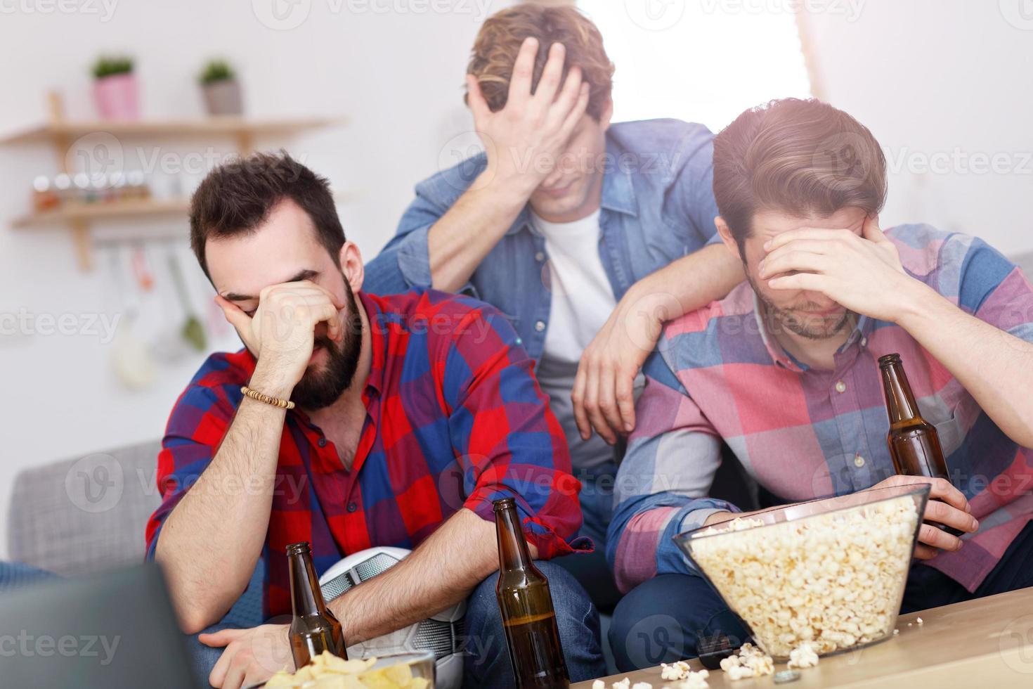 triste grupo masculino de amigos viendo deportes en la televisión en casa foto