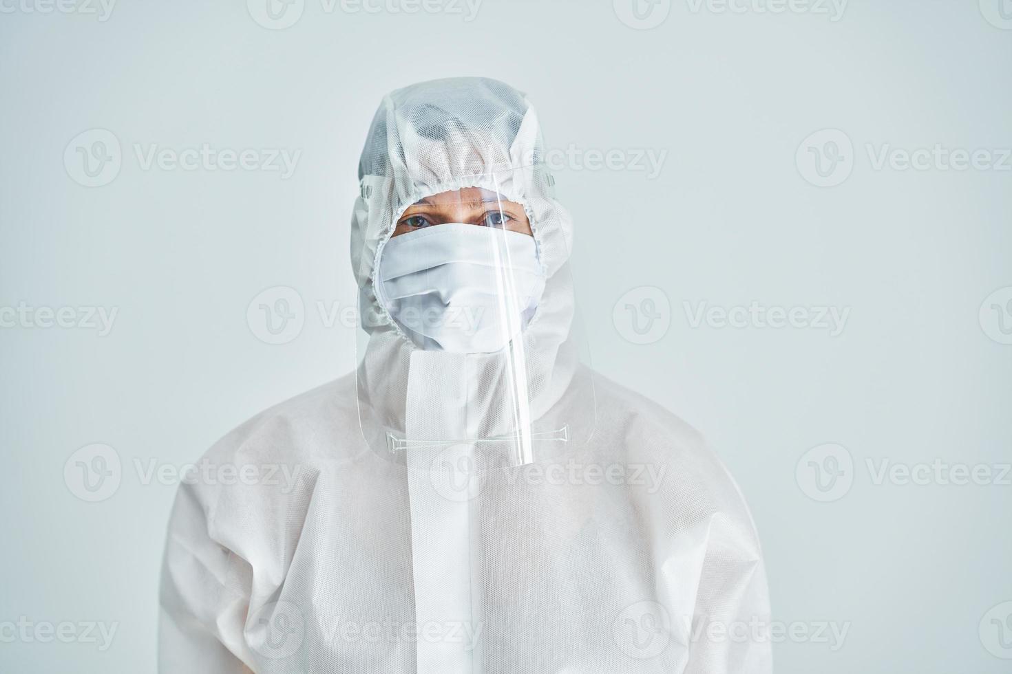 Woman in bio-hazard suit and face shield on white background. photo