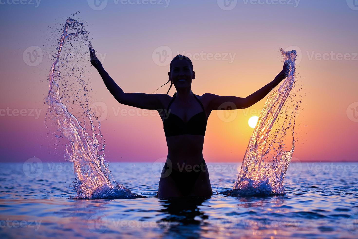 Silhouette of young woman practicing yoga on the beach at sunrise photo