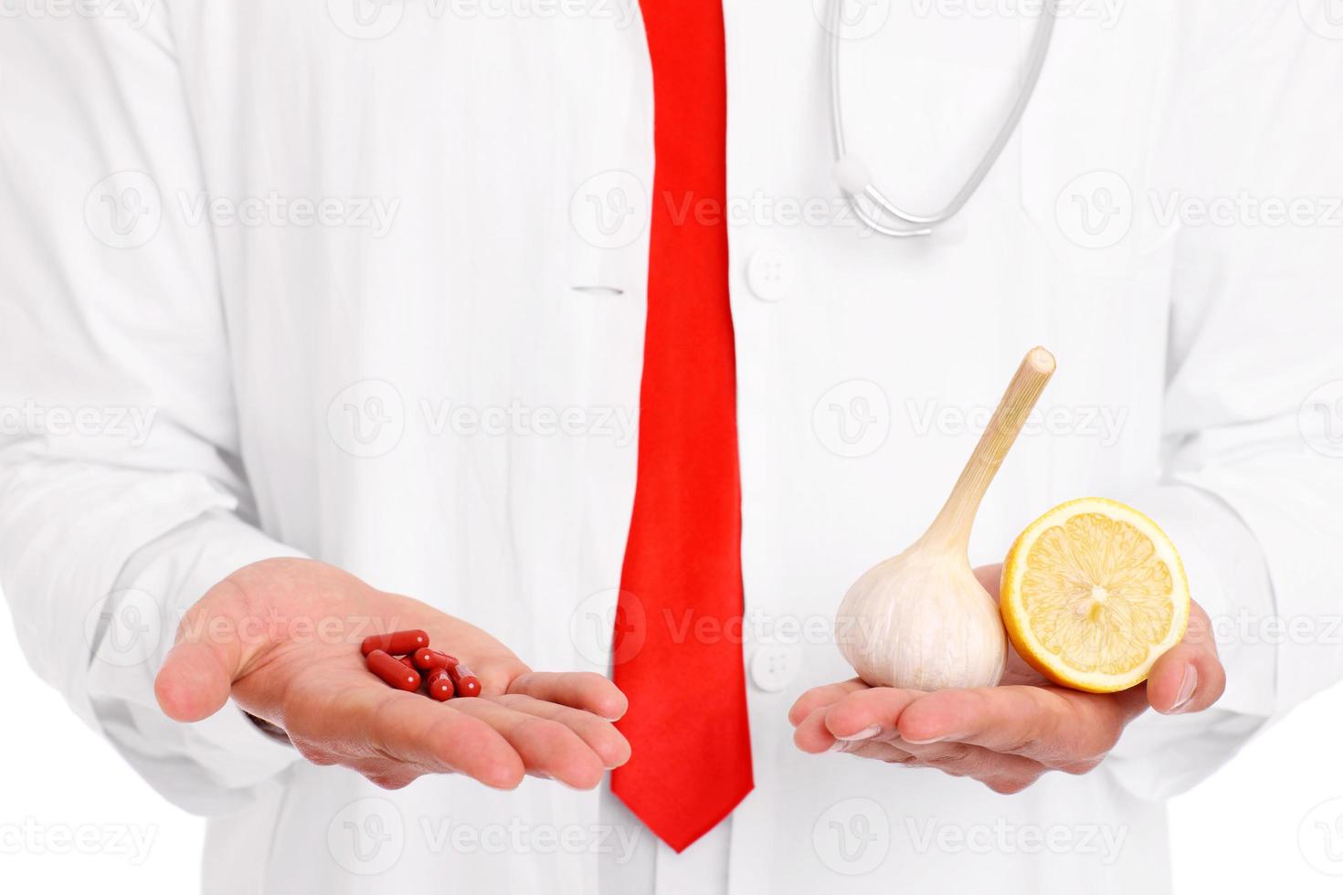 Midsection of a doctor holding pills and garlic with lemon photo