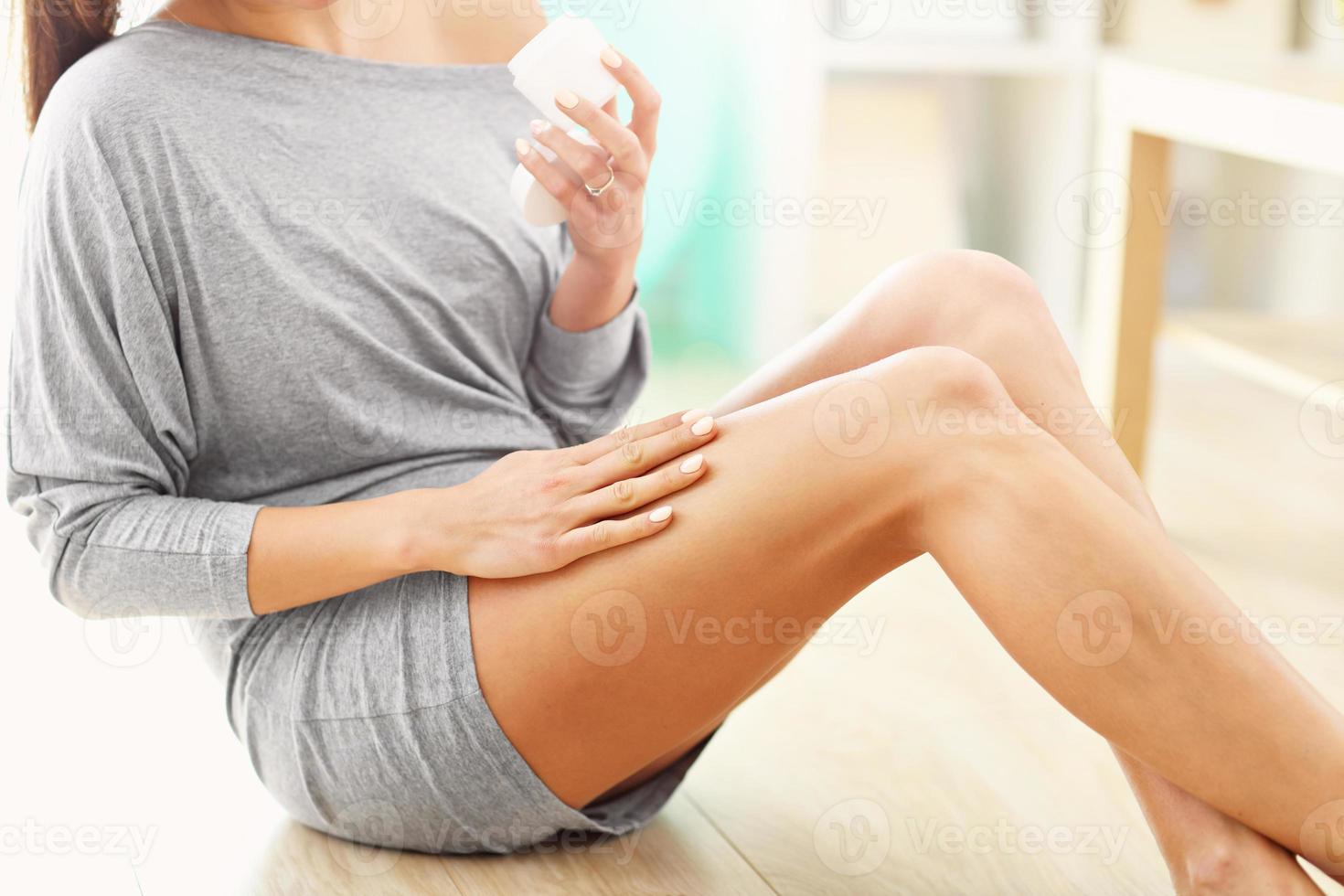 Woman using body lotion on her legs photo