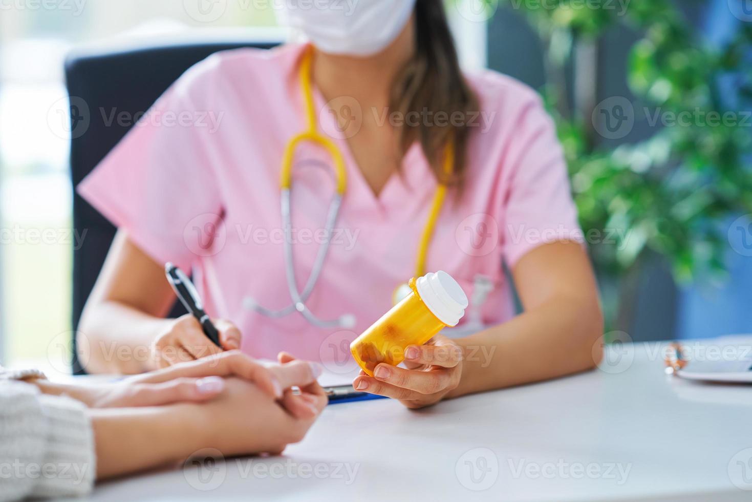 Doctor in mask explaining diagnosis to her female patient photo