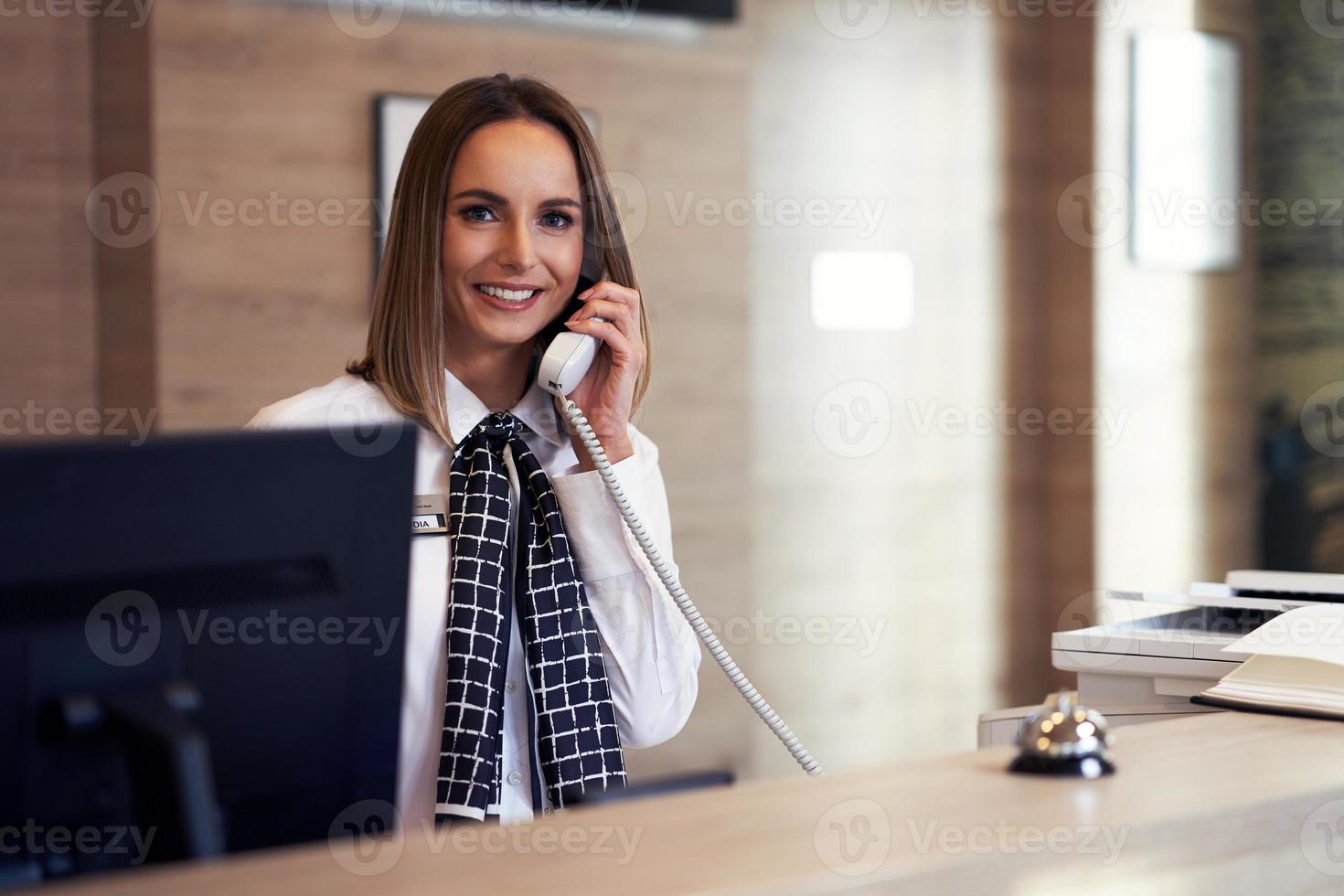 Receptionist answering phone at hotel front desk photo