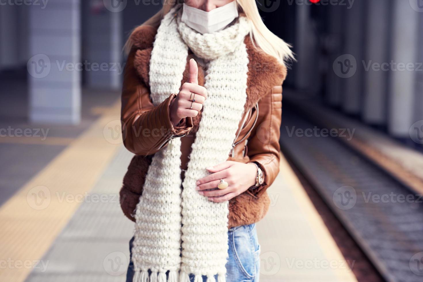 Adult woman at train station wearing masks due to covid-19 restrictions photo