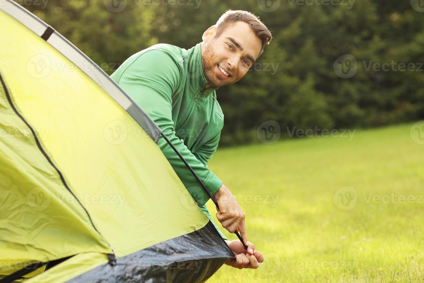 Young man putting up tent photo