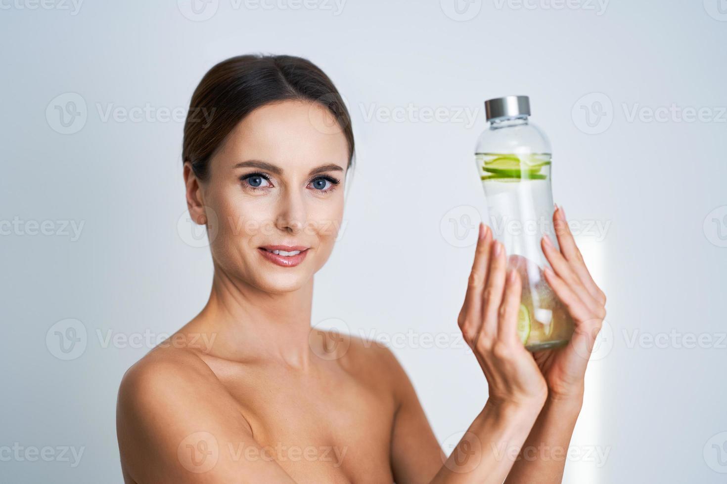 Beautiful adult woman posing with cucumber water over white background photo