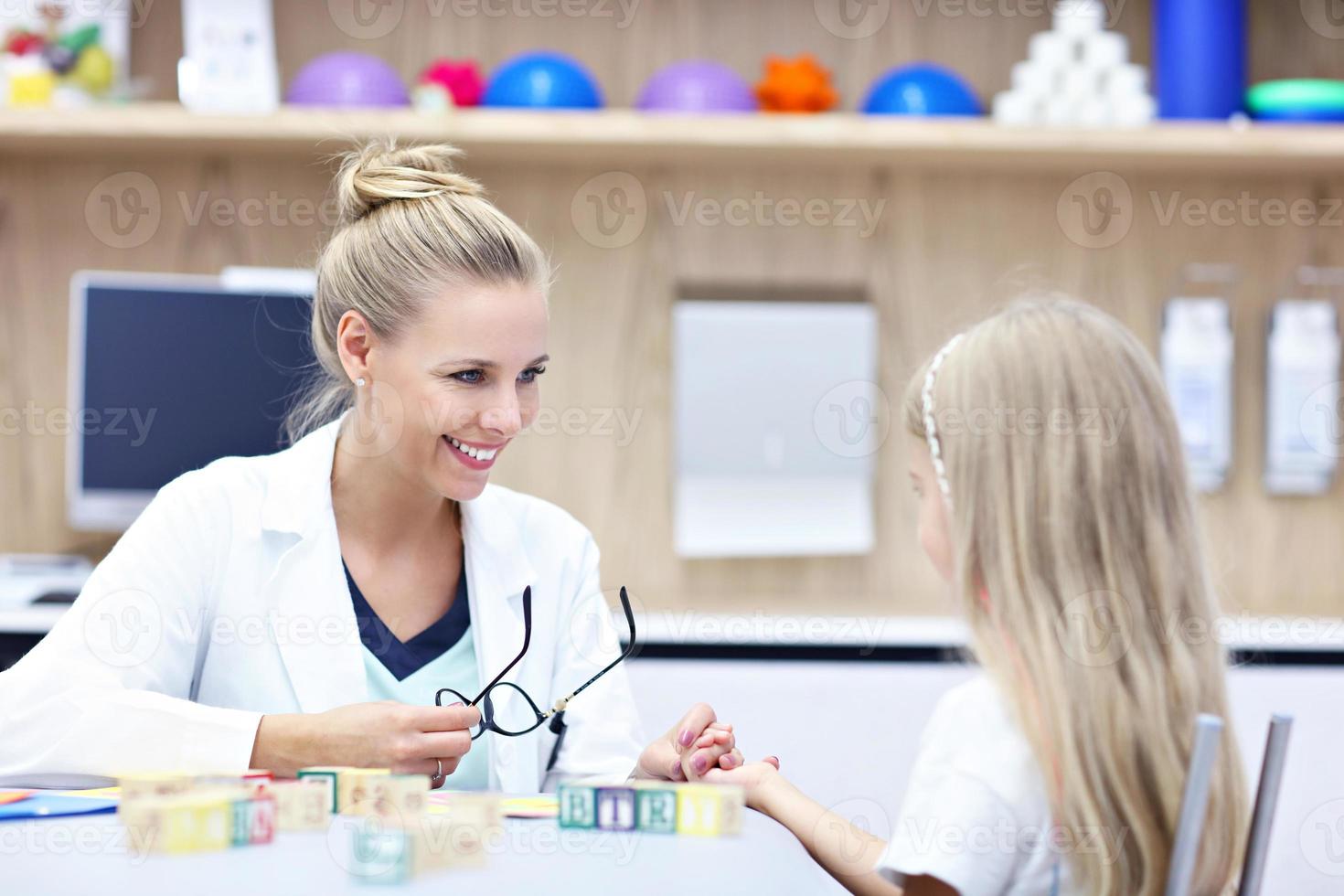 Child psychologist working with young girl in office photo