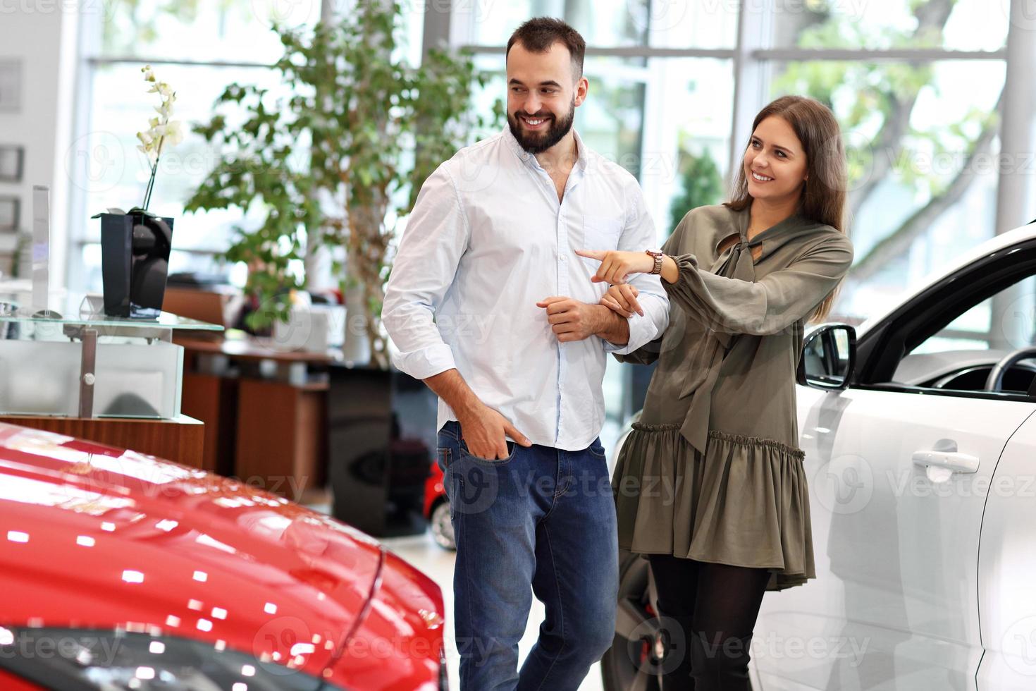 Adult couple choosing new car in showroom photo