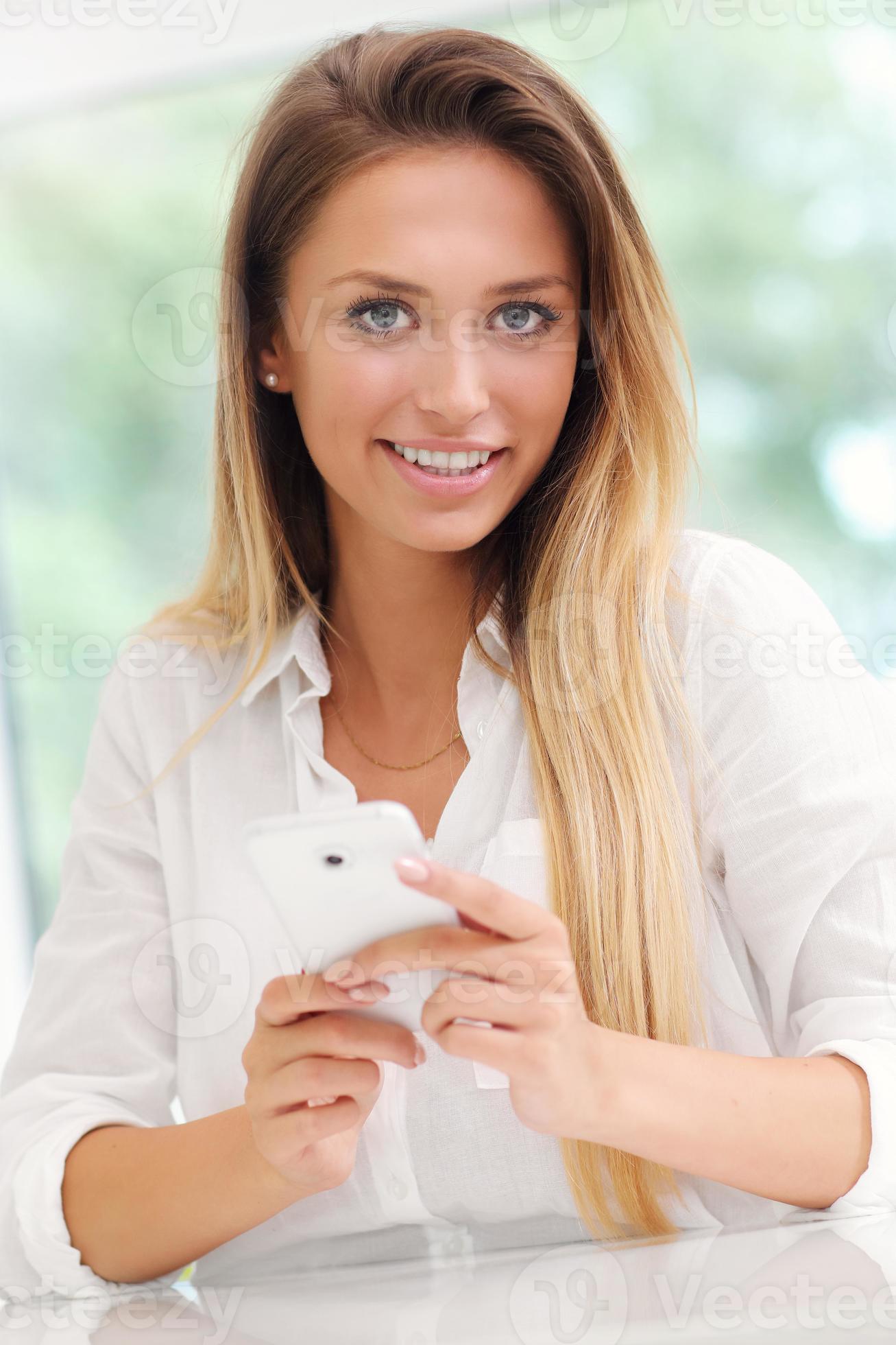 Young woman with smartphone in kitchen 15853080 Stock Photo at Vecteezy
