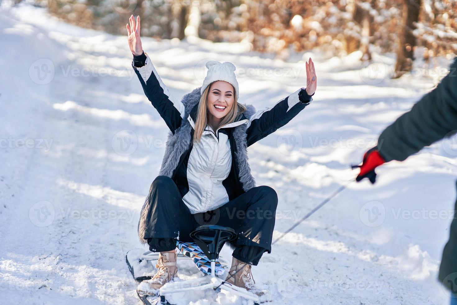 Couple having fun with sledge on snow in winter photo