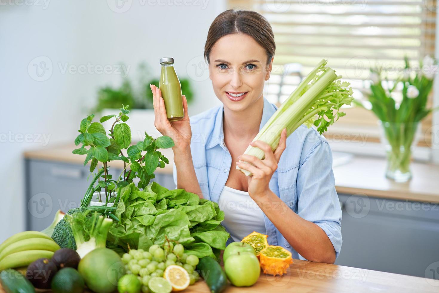 Healthy adult woman with green food in the kitchen photo