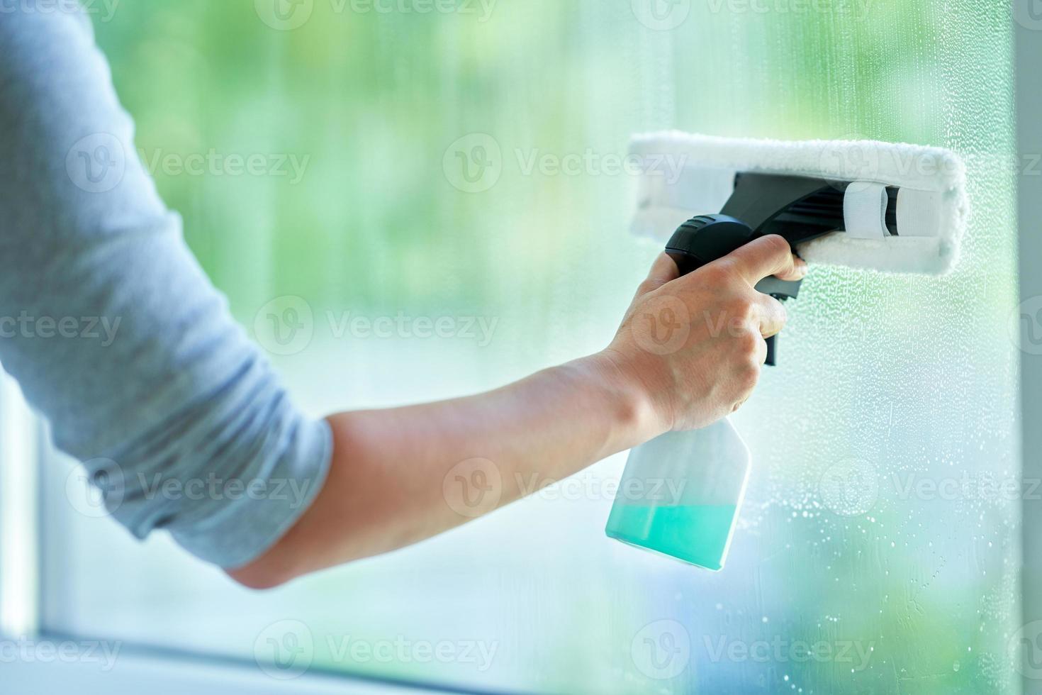 mujer joven limpiando la ventana en la cocina foto