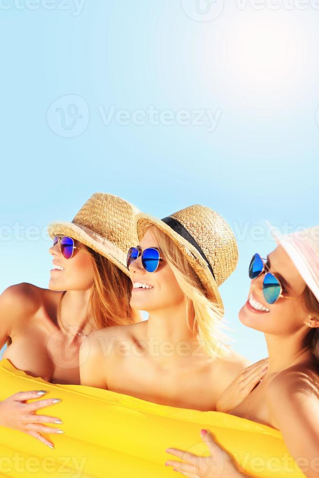 Group of women having fun with mattress on the beach photo