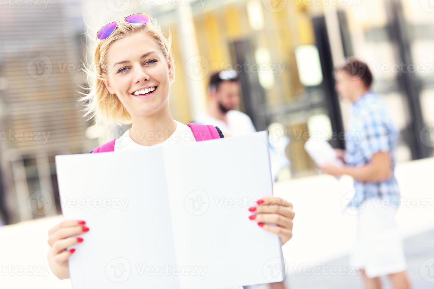 Young student standing in the campus with an open notebook photo