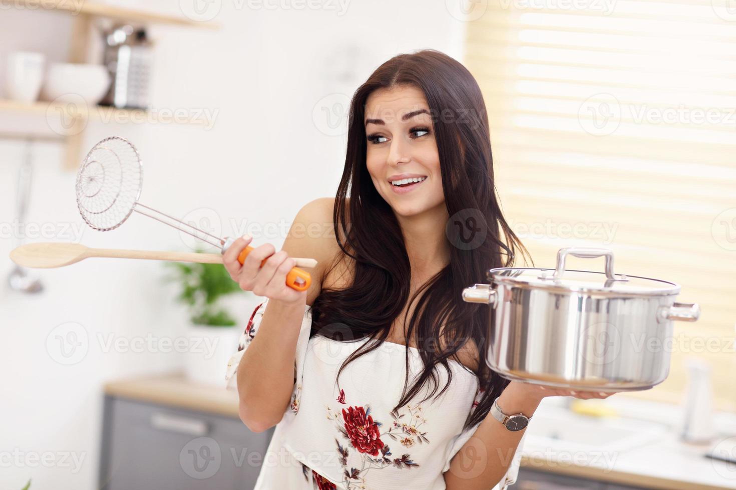 mujer joven tratando de cocinar algo en la cocina foto