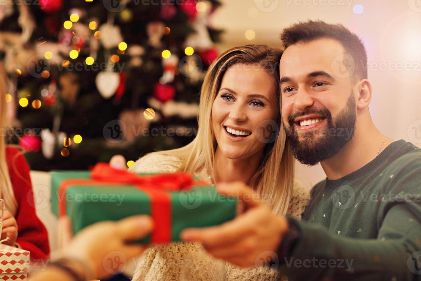 Group of friends giving Christmas presents at home photo