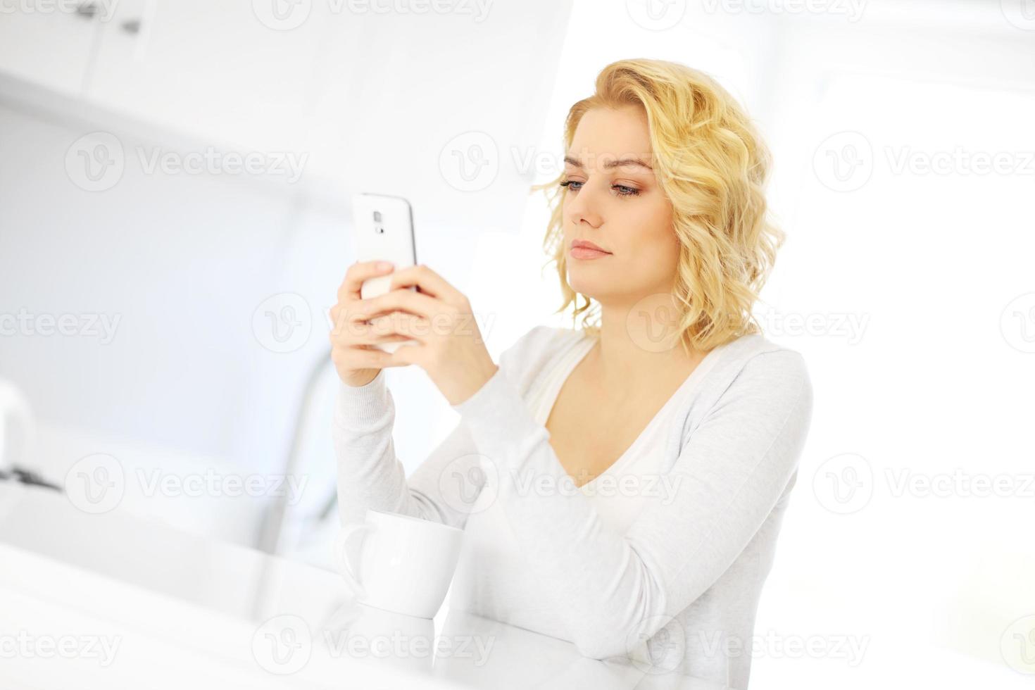 mujer joven con smartphone en la cocina foto