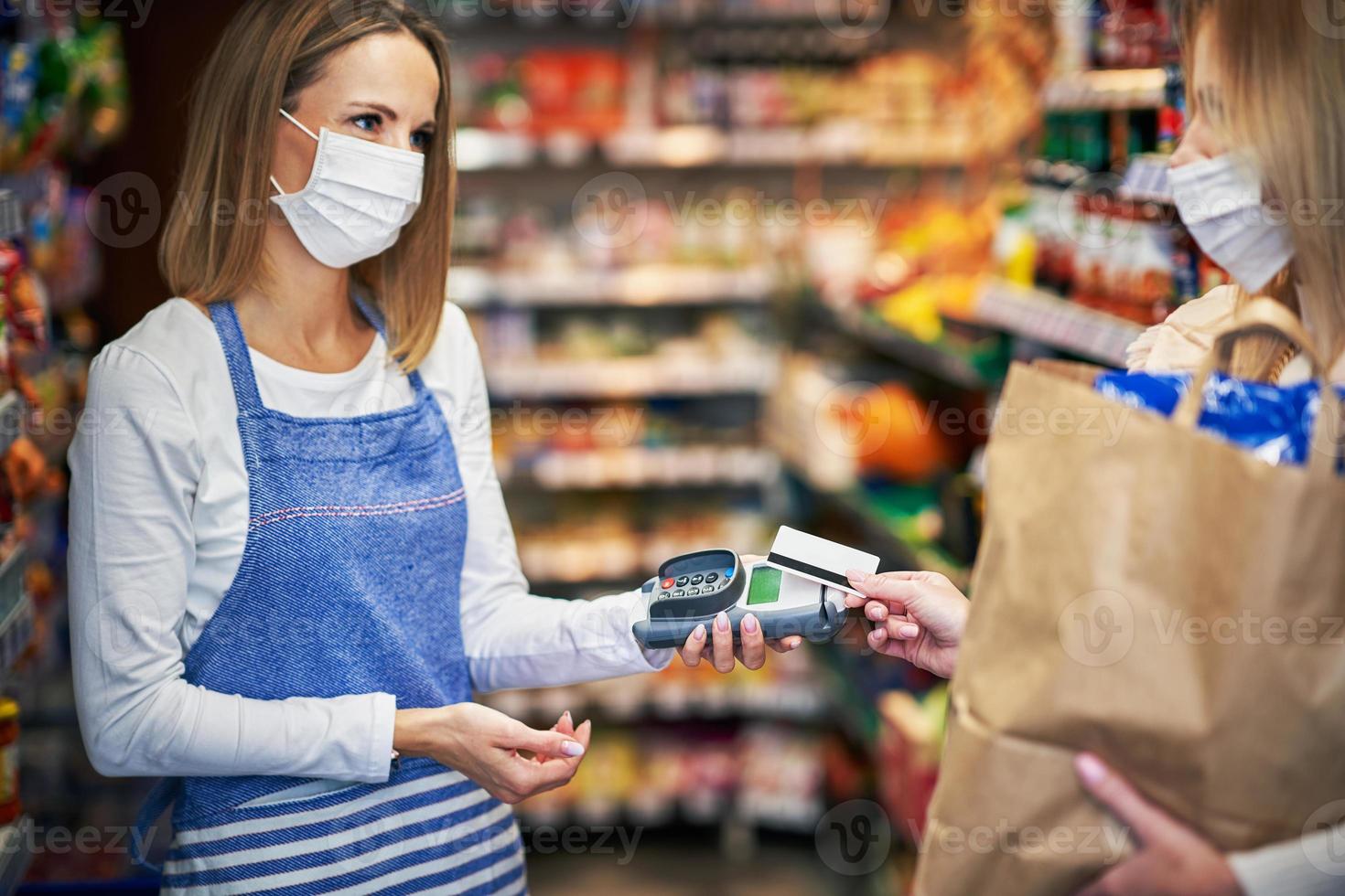 Adult woman in medical mask picking up order in grocery store photo