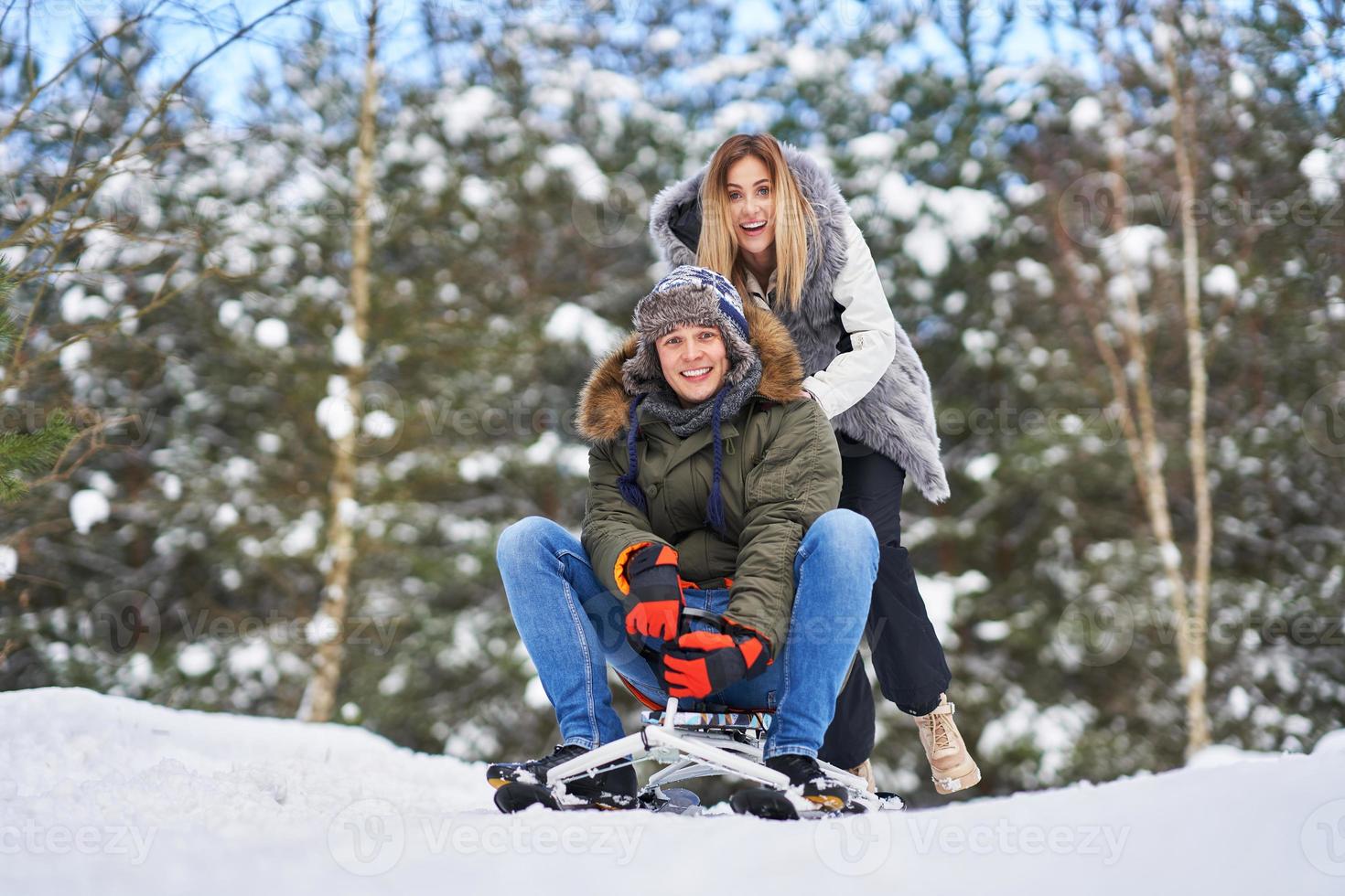 Couple having fun with sledge on snow in winter photo