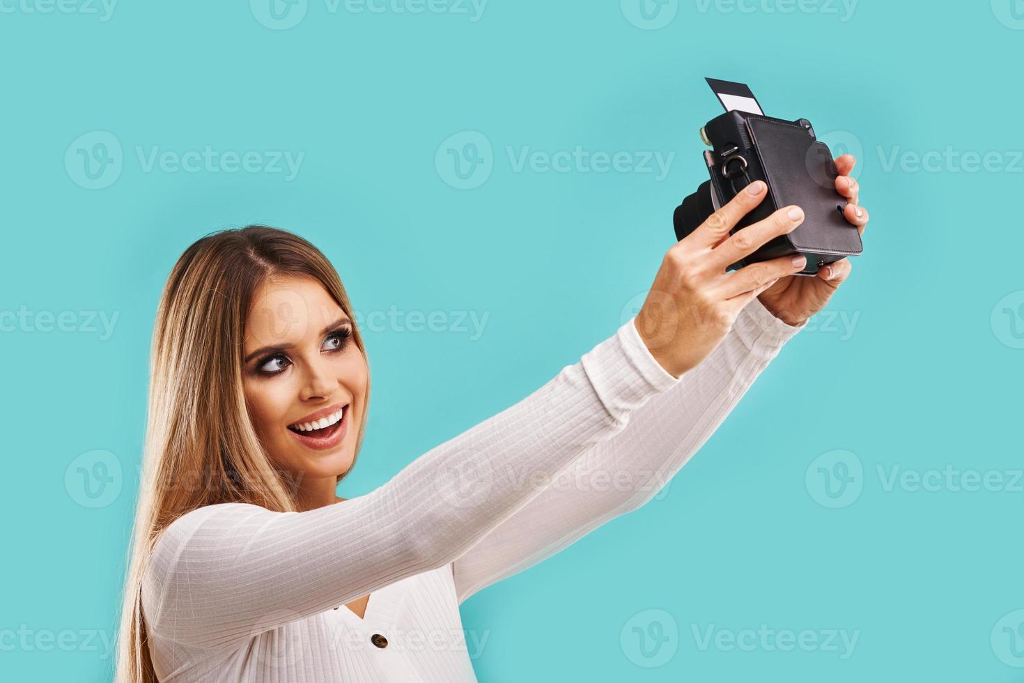 Beautiful adult woman posing over blue background taking instant photos