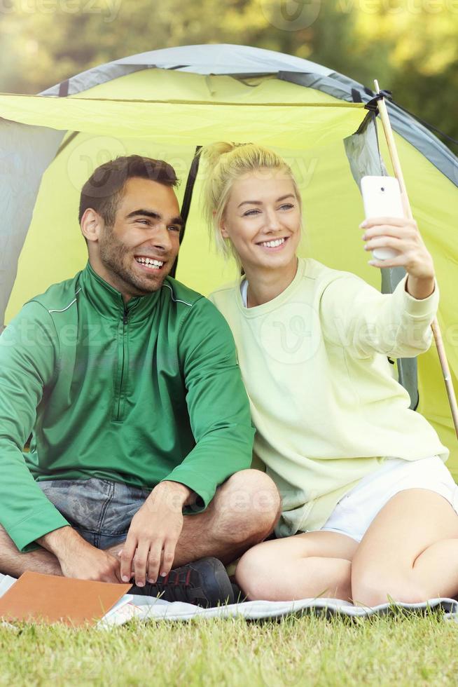 Couple camping in forest and taking selfie photo