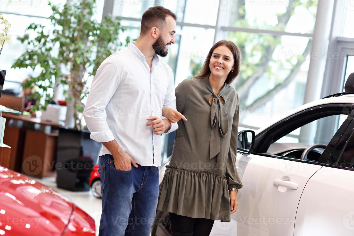 Adult couple choosing new car in showroom photo