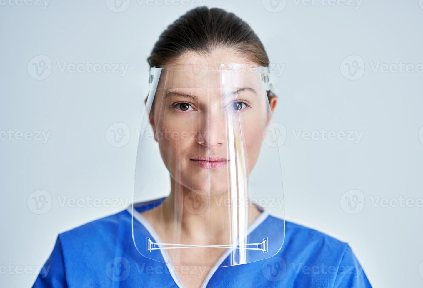 Close up portrait of female medical doctor or nurse wearing face shield photo