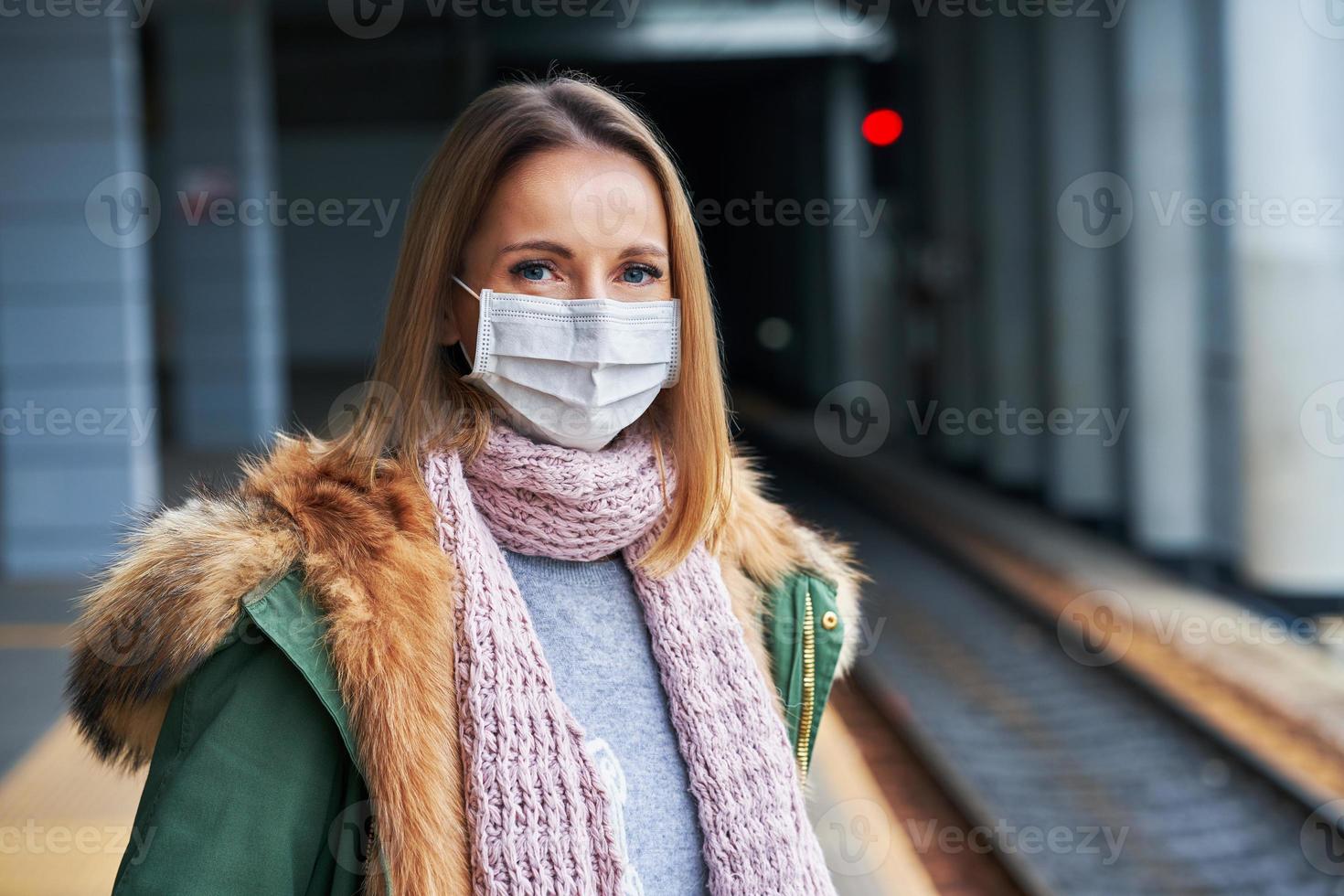 Adult woman at train station wearing masks due to covid-19 restrictions photo