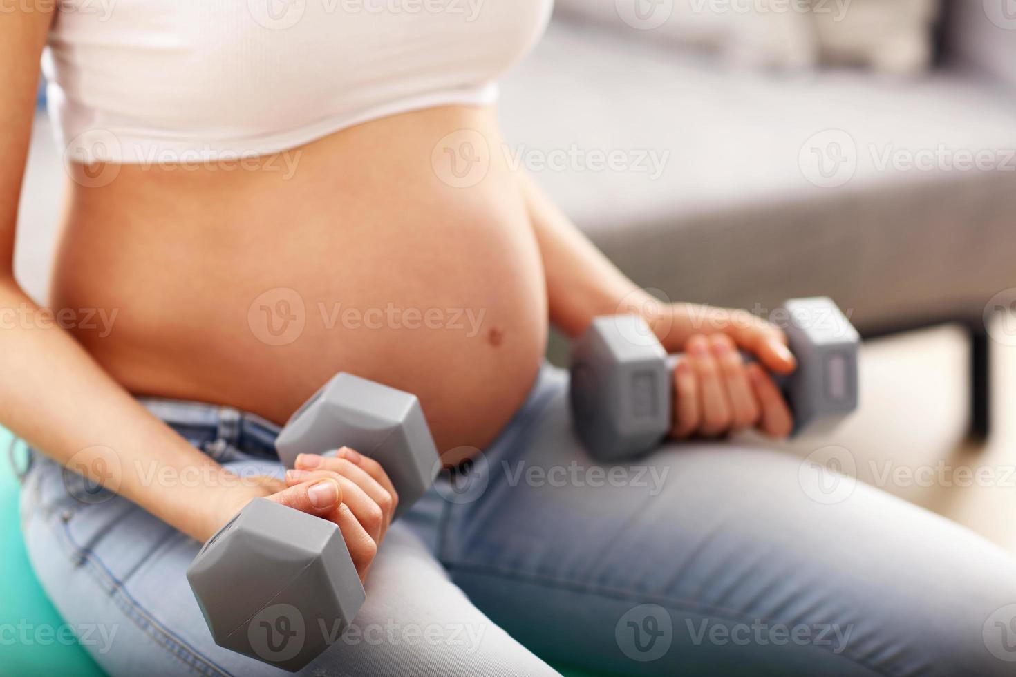 Beautiful pregnant woman doing exersice using dumbell photo