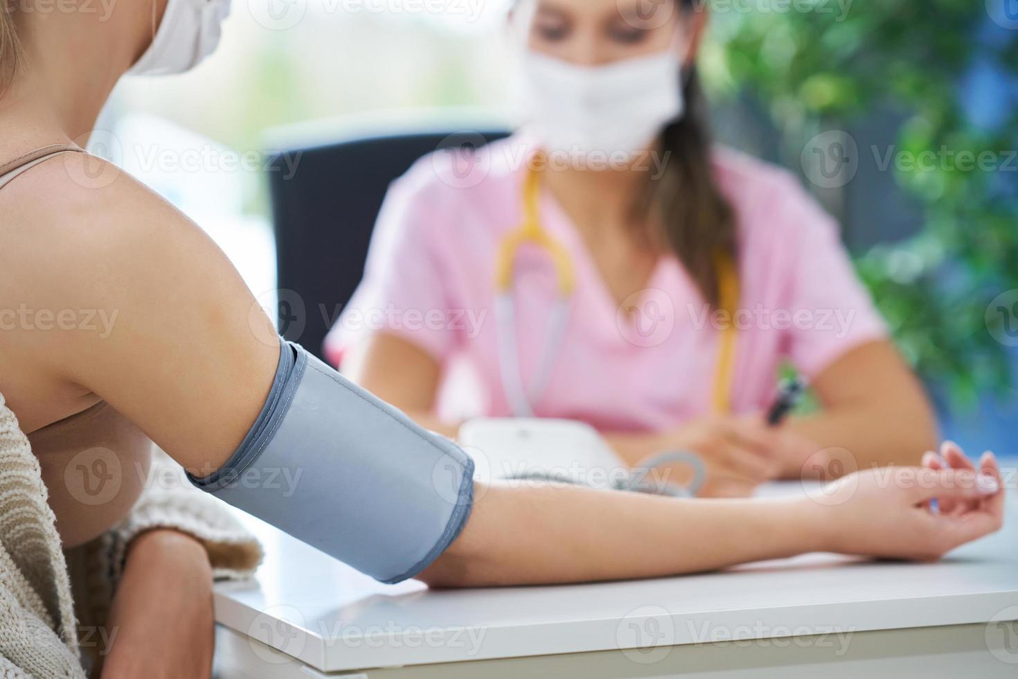 Doctor in mask explaining diagnosis to her female patient photo