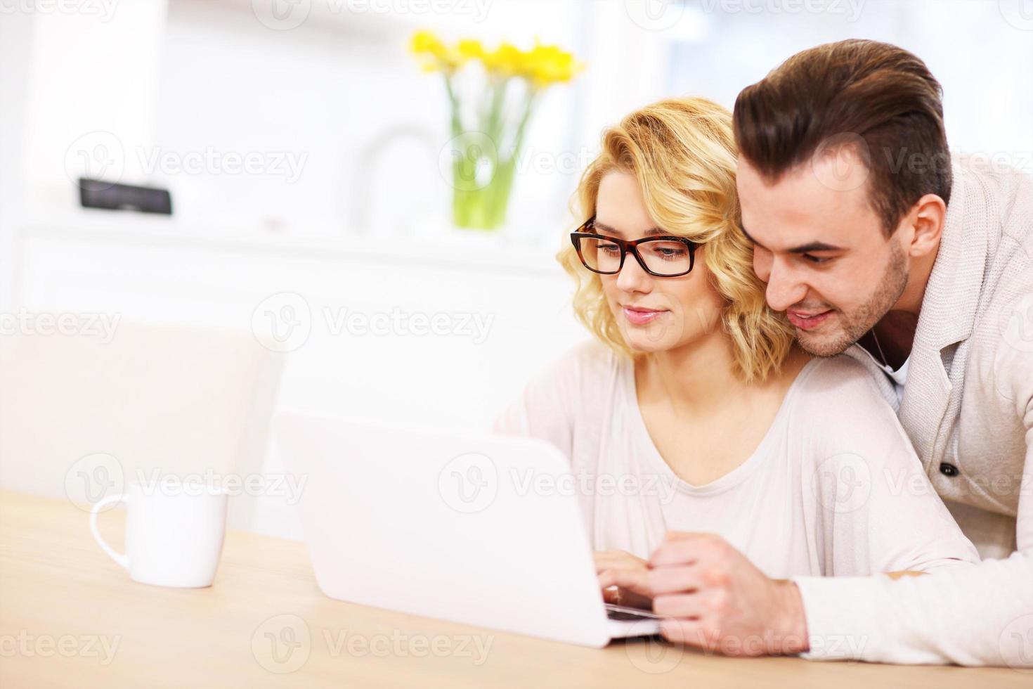 Happy couple using laptop at home photo