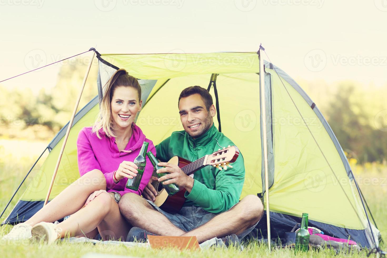 Couple camping in forest and playing guitar photo
