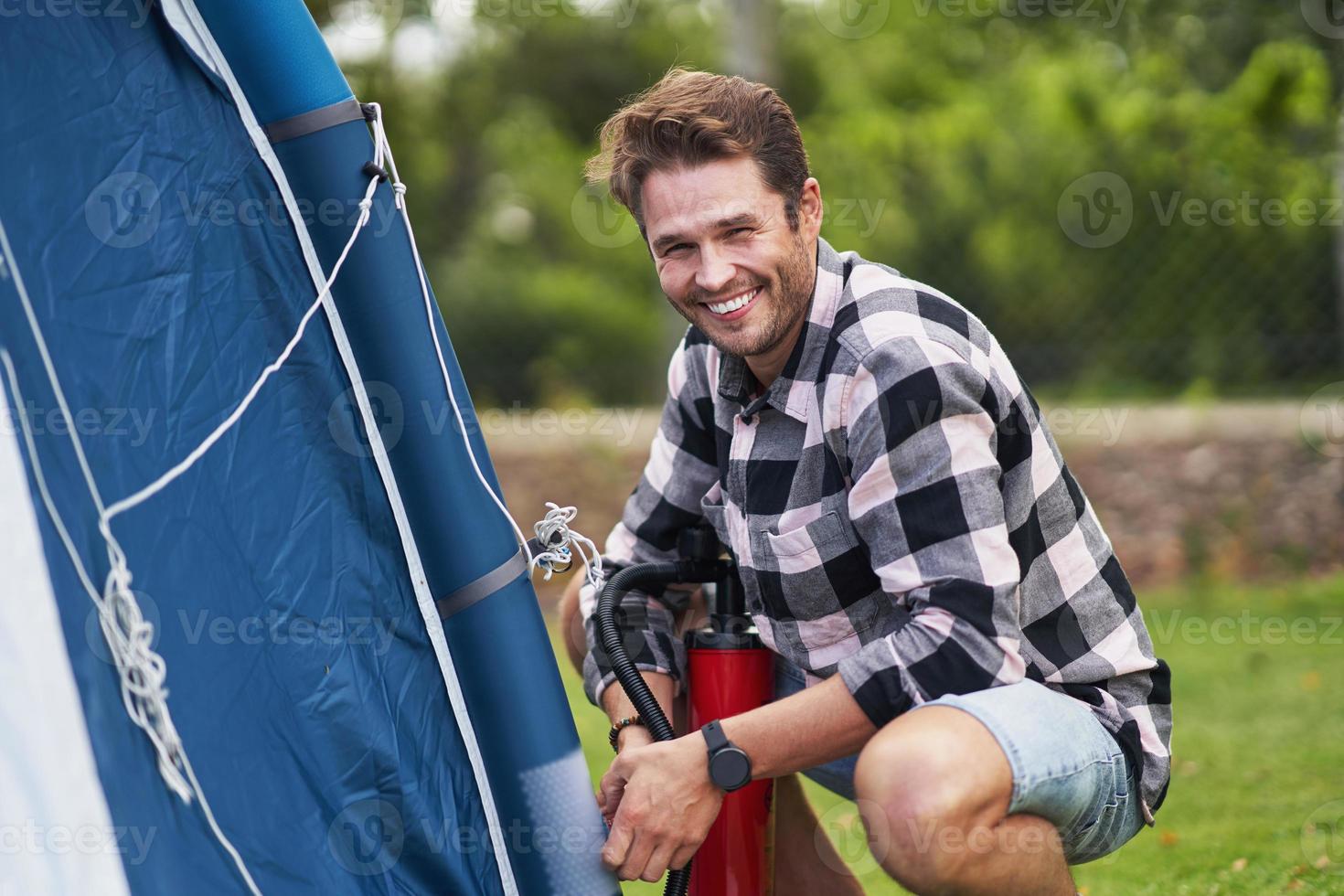 Young nice couple having fun on camping setting up tent photo