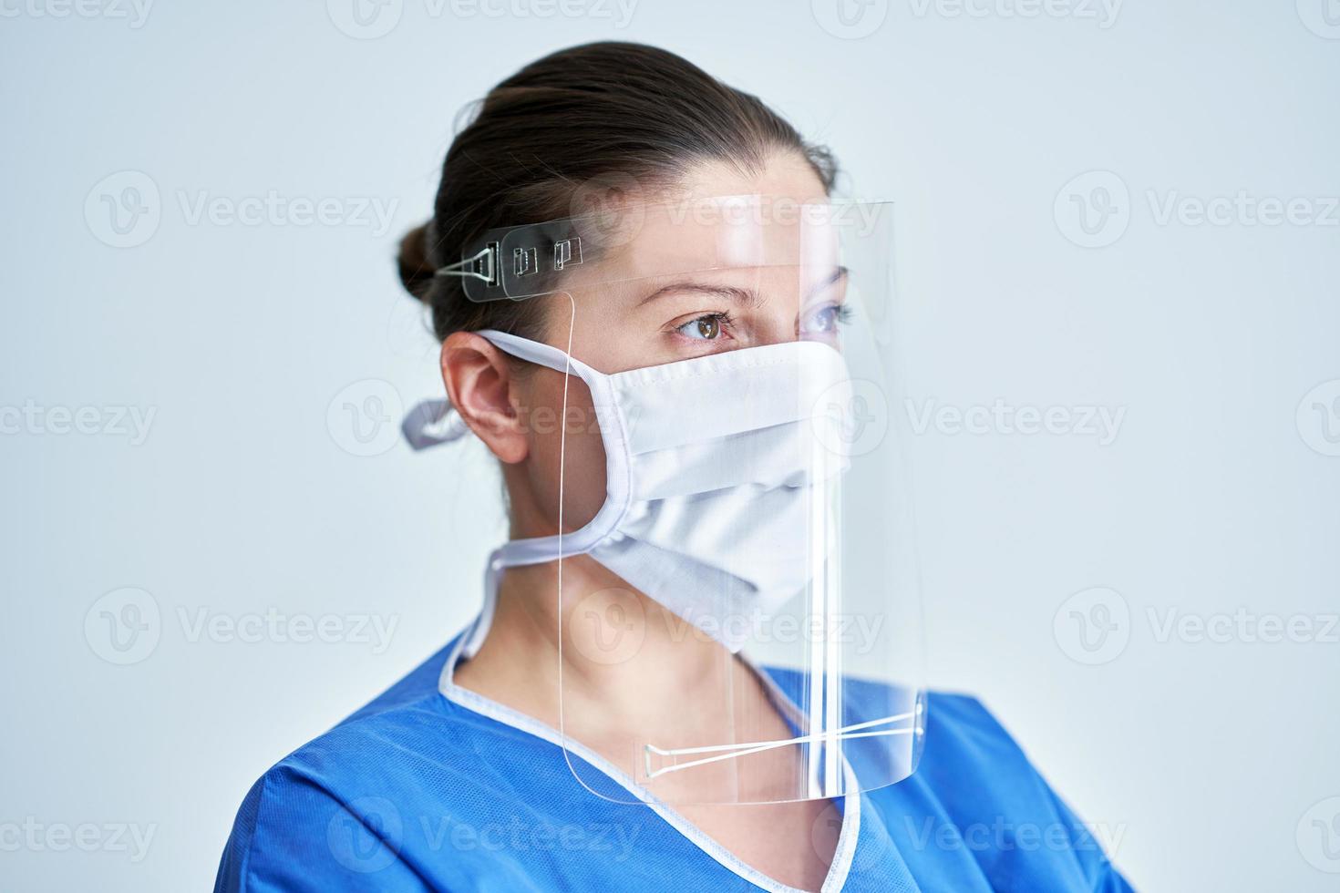 Portrait of female medical doctor wearing protective mask and face shield photo